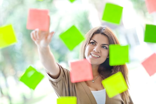 Multitask woman pointing at post-its and smiling