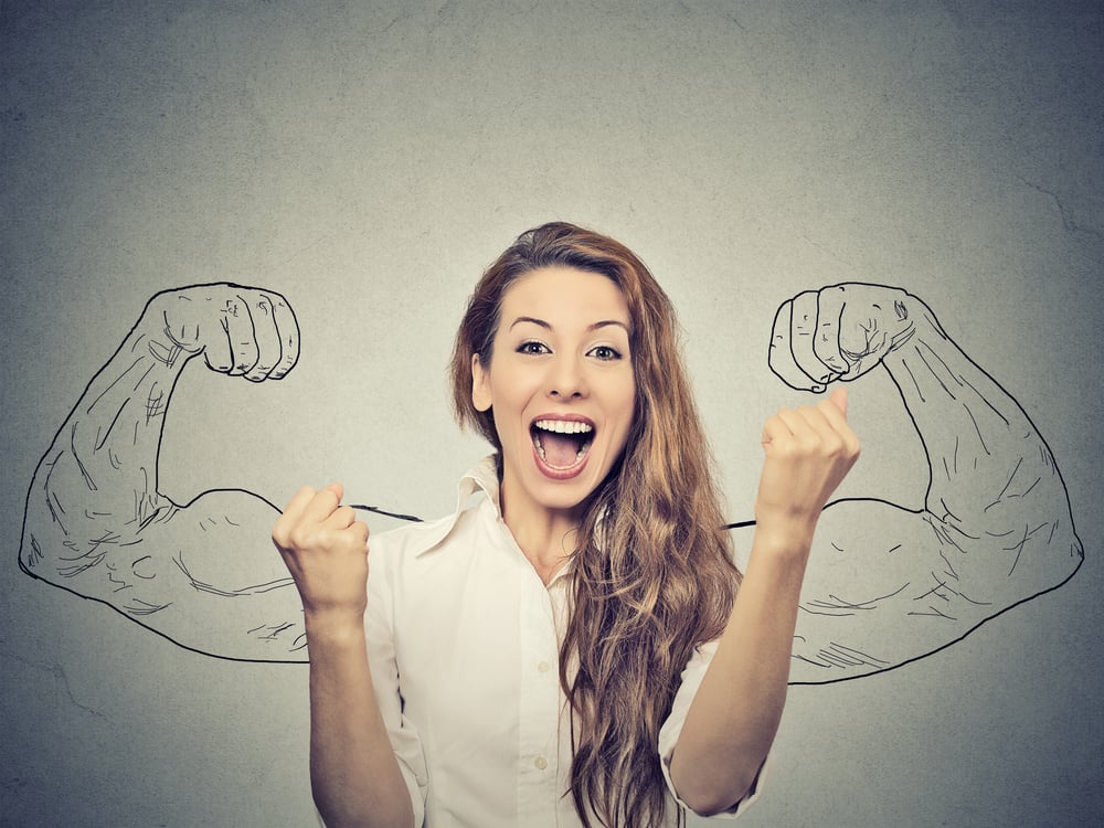 happy woman exults pumping fists ecstatic celebrates success on gray wall background